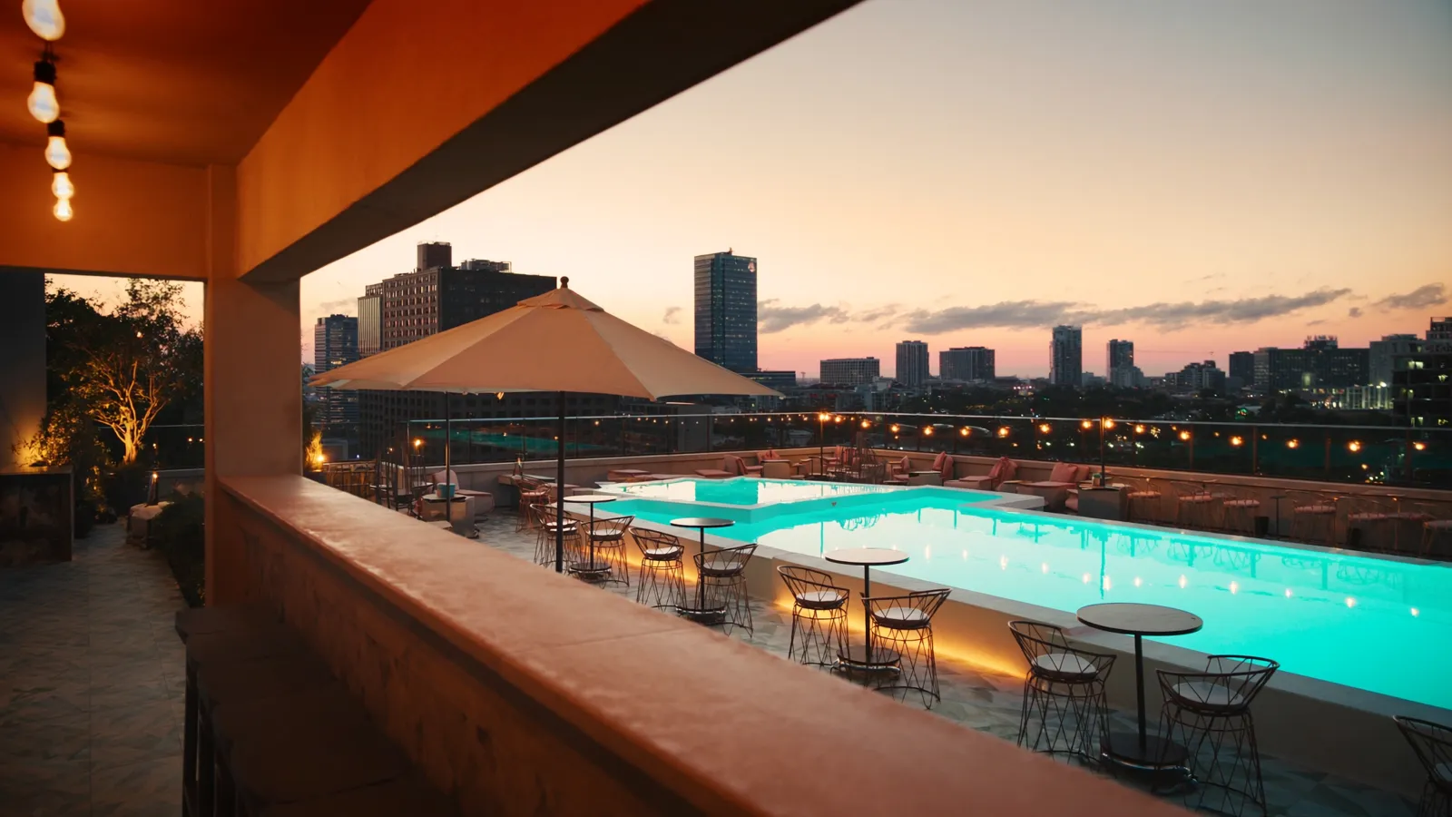 Rooftop pool terrace in Dallas at sunset with the downtown skyline behind
