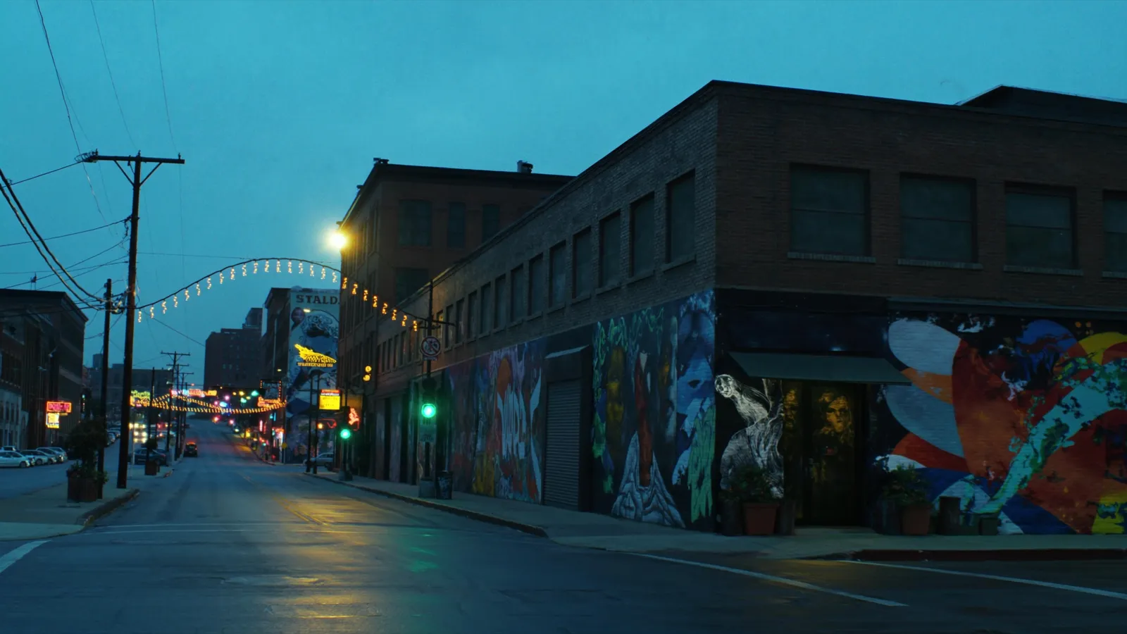 Deep Ellum Dallas at dusk with large-scale murals and neon on brick warehouse buildings
